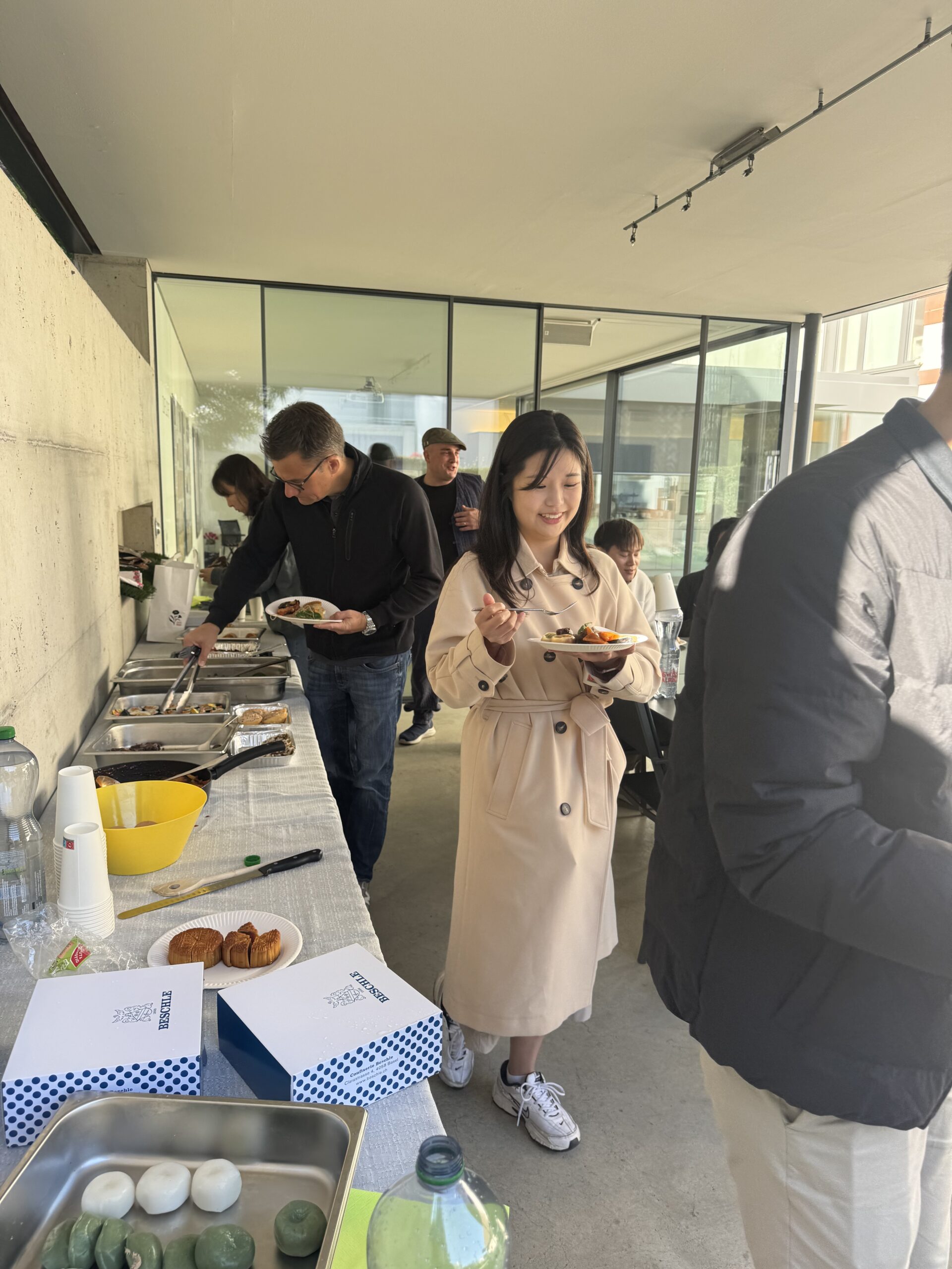 Community members serving food from diverse cultural dishes at Friends of Korea potluck buffet table